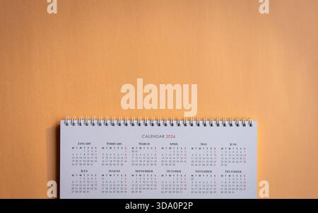 calendrier de table 2026 sur le dessus d'un fond de papier ordinaire de couleur orange. Vue de dessus, espace de copie. Banque D'Images