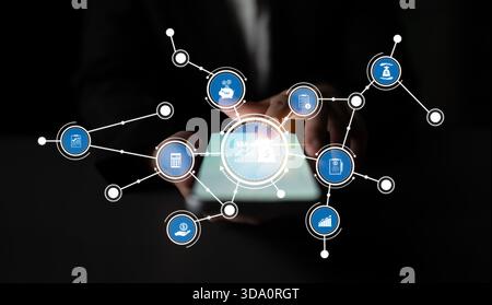 Une personne tient une tablette numérique affichant diverses icônes d'affaires connectées par des liens de données, symbolisant l'intégration de la technologie et Banque D'Images