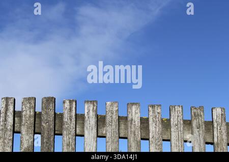 Clôture en bois contre un ciel bleu avec fond abstrait de nuages Banque D'Images