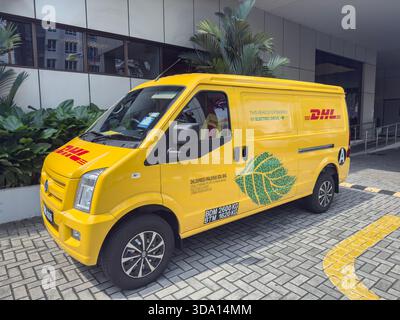 Penang, Malaisie - 25 juin 2025 : un fourgon de livraison jaune avec motif de feuilles vertes est garé sur le trottoir pavé Banque D'Images