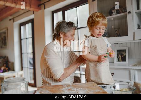 Cuisson de vacances en famille avec grand-mère dans la cuisine confortable. Banque D'Images