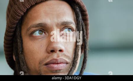 Homme afro-américain regardant hors caméra portant un bonnet marron, chemise bleue en studio, espace copie Banque D'Images
