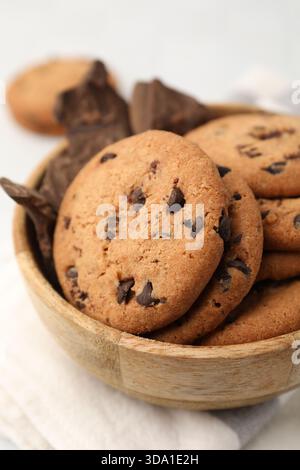 Délicieux biscuits aux pépites de chocolat et morceaux de chocolat dans un bol sur une table blanche, gros plan Banque D'Images