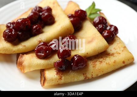 Crêpes savoureuses aux cerises et à la menthe sur la table, gros plan Banque D'Images