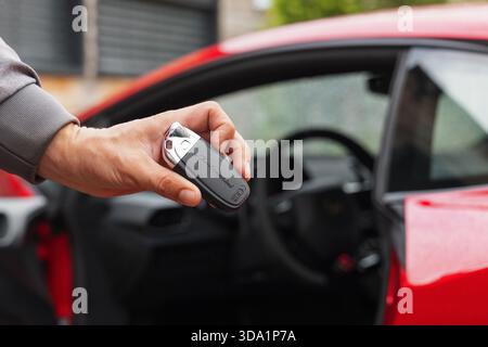 Slovénie, Ljubljana - 9 octobre 2025 : clé Lamborghini Huracan STO tenue par un concessionnaire près d'une voiture de sport rouge. Banque D'Images