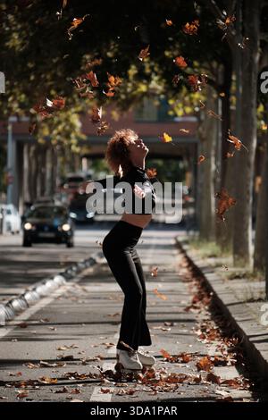 Jeune femme patinant à roulettes appréciant la chute des feuilles d'automne Banque D'Images