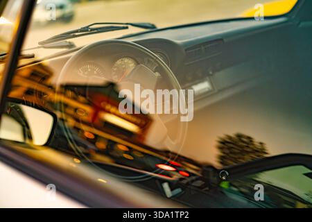 VO, italie 28 octobre 2025 : intérieur classique porsche avec tableau de bord, volant et jauges, reflets de pare-brise des lumières de la ville et bokeh Nightsc Banque D'Images