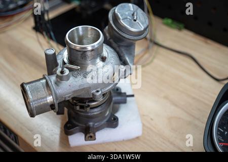 Rome, italie, 20 novembre 2025 : turbocompresseur usagé sur un banc d'atelier prêt à être inspecté, réparé ou installé dans un moteur automobile, gros plan Banque D'Images