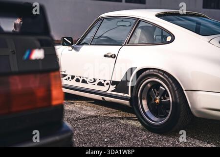 VO, italie 28 octobre 2025 : porsche 911 carrera blanche et bmw m noire garées côte à côte sur asphalte, mettant en valeur le style vintage, l'ingénierie allemande et Banque D'Images