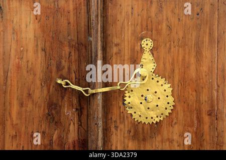 Poignée de porte en métal sur vieille porte en bois brun. La poignée de porte est peinte en or. Banque D'Images