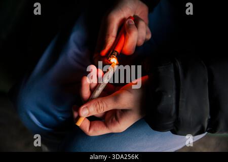 Les mains d'un homme allumant une cigarette de marijuana avec un briquet Banque D'Images