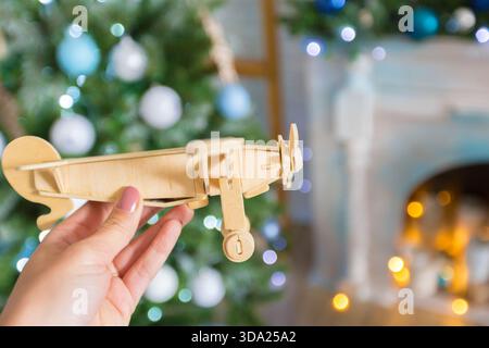 Modèle d'avion en bois tenu à la main avec arbre de Noël en arrière-plan Banque D'Images