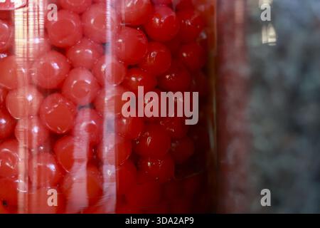 Gros plan macro de sphères de bonbons rouges éclatants dans le pot. fond de confiserie sucrée plein de friandises rondes au sucre, créant coloré et nost Banque D'Images