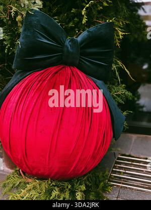 boule de noël géante en velours rouge avec noeud vert foncé en extérieur Banque D'Images