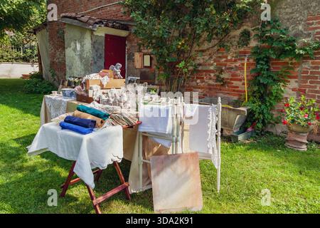 Stand de marché aux puces présentant des draps vintage, des articles pour la maison et des décors lors d'une vente en plein air Banque D'Images