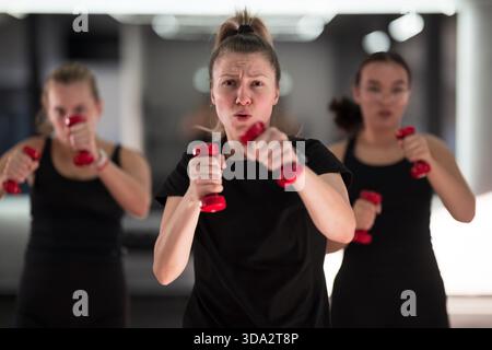 Groupe de femmes participent activement à un cours de fitness, axé sur leur entraînement avec de petits haltères. || autorisation du modèle Banque D'Images