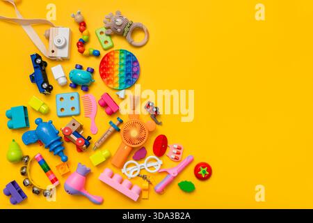 Beaucoup de jouets pour enfants différents sur un fond jaune avec un espace pour le texte, vue de dessus, pose à plat Banque D'Images