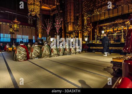 Les moines bouddhistes en robes de cérémonie brodées d'or (kesa) s'agenouillent sur des tatamis pendant la cérémonie du matin (Oasaji) au temple Zenkoji, Nagano, préfecture de Nagano, Japon. Zenkoji (善光寺 ?) a été fondée au VIIe siècle et, selon la tradition, abrite la plus ancienne sculpture bouddhiste du Japon ; la cérémonie quotidienne du matin est ouverte au public. L'autel richement doré et les lanternes suspendues dans le hall principal (Hondo) sont caractéristiques du temple, qui est administré conjointement par les écoles de bouddhisme Tendai et Jodo-Shu Banque D'Images