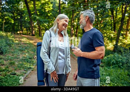 Un couple joyeux se promène sur un sentier pittoresque entouré de verdure vibrante, favorisant la santé et le bien-être par des activités de plein air amusantes, renforçant le Banque D'Images