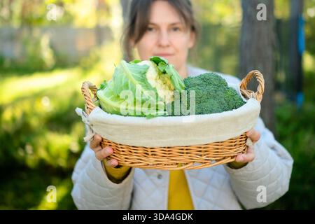 Jeune agricultrice joyeuse avec panier de chou-fleur et brocoli. Saison des récoltes, légumes maison, alimentation riche en fibres, produits de saison et délicieuses recettes pour des repas sains. Banque D'Images
