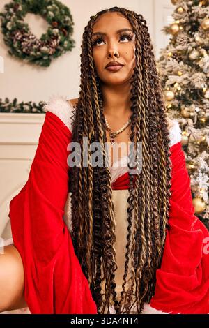 Femme avec de longs cheveux tressés portant une tenue festive de père Noël rouge et blanc pour le portrait de vacances de Noël Banque D'Images
