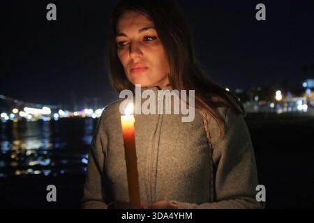 Femme tenant la bougie allumée la nuit sentant l'espoir et la paix Banque D'Images