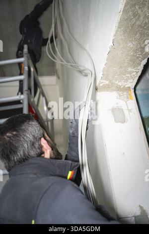 Un ouvrier pose des câbles le long d'un mur dans une pièce rénovée, électricien, nouveau bâtiment, Allemagne Banque D'Images