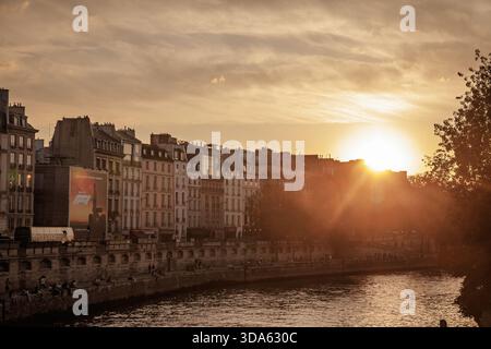 PARIS, FRANCE - 22 JUIN 2025 : coucher de soleil sur la Seine près de Rive gauche à Paris, France, avec des bâtiments de style haussmannien bordant les quais, les gens se détendent Banque D'Images