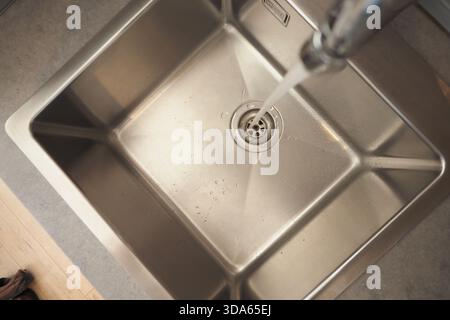 L'eau s'écoule du robinet dans l'évier de la cuisine Banque D'Images