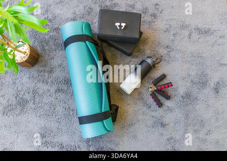 Composition à plat de yoga moderne et des essentiels de fitness sur un tapis gris doux. Banque D'Images