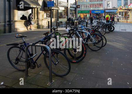 Vélos garés dans des stands de vélos métalliques dans le centre-ville de Cardiff par une journée d'hiver chargée, pays de Galles. Banque D'Images