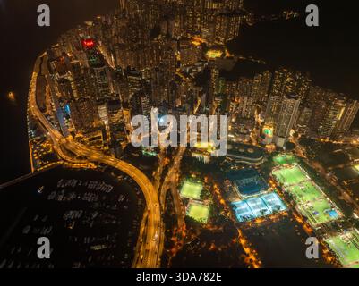 Vue aérienne d'un paysage urbain vibrant scintillant de lumières, d'autoroutes tissant à travers des bâtiments imposants et des zones de loisirs, île de Hong Kong, Hong Kong Banque D'Images