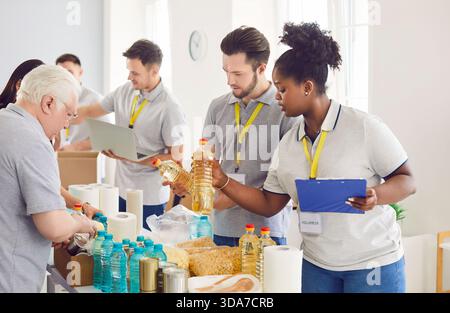 Divers bénévoles regroupent le tri des dons de denrées alimentaires dans des boîtes en carton pour la collecte de nourriture caritative Banque D'Images