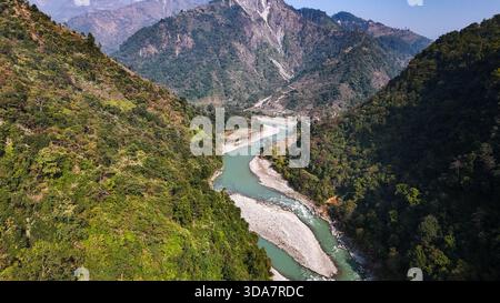 Vue aérienne de la rivière serpentine serpentant à travers la vallée accidentée le long de l'autoroute Prithvi, embrassée par les collines verdoyantes, Pokhara, Népal. Banque D'Images