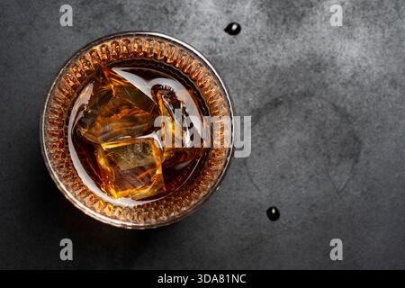 whisky sur les rochers dans un verre placé sur une surface texturée sombre Banque D'Images