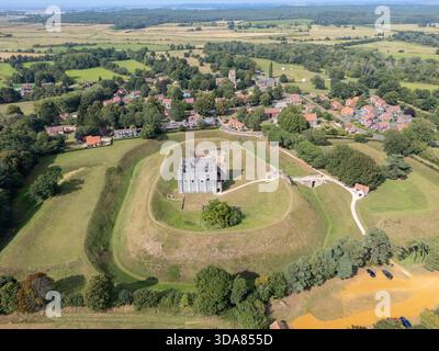 Vue aérienne des ruines de pierre de Castle Rising se dressent fièrement au sommet de son monticule herbeux, encadré par le village pittoresque et les vastes champs ouverts au-delà, King's. Banque D'Images