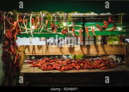 Paro, Bhoutan - 17 septembre 2025 : vue de piments rouges vibrants qui séchent sous les avant-toiTS, une cascade enflammée sur fond vert frais. Banque D'Images
