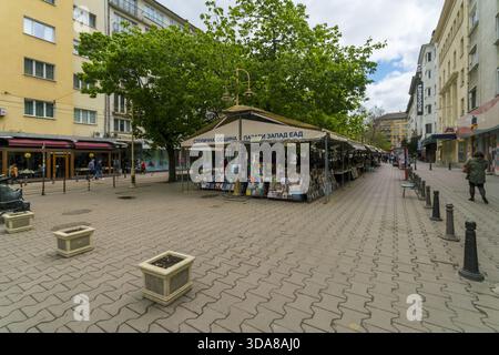 Sofia, Bulgarie - 06 mai 2017 : vue sur le marché animé du livre à l'ombre d'arbres verts, le trottoir s'étendant vers des bâtiments lointains. Banque D'Images