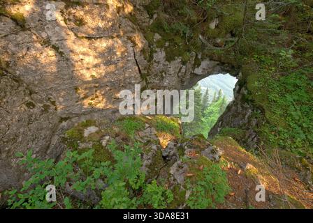 Vue aérienne de la formation rocheuse accidentée d'Ohniste, son arc encadrant une vue d'arbres verdoyants contre les collines lointaines, Liptovsky Jan, région de Zilina, S. Banque D'Images