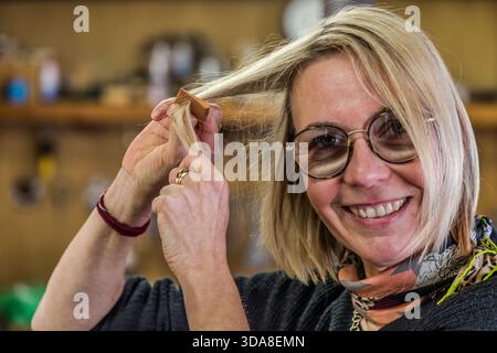 Une femme sourit en essayant un peigne en bois fraîchement fabriqué dans un atelier de peigne traditionnel à Kiso, préfecture de Nagano, Japon Banque D'Images