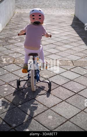 Fille de quatre ans apprenant à monter un vélo Banque D'Images