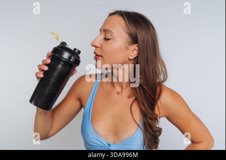 Femme en tenue d'entraînement tenant une bouteille shaker, posant avec confiance. Banque D'Images