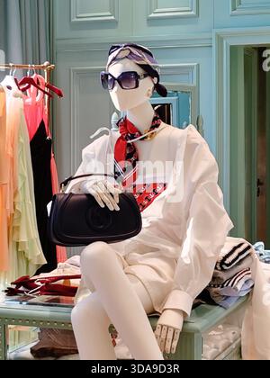 Cannes, France - 7 juin 2025 : mannequin boutique Gucci portant une tenue blanche et tenant un sac à main noir dans un magasin de luxe sur la Croisette Banque D'Images