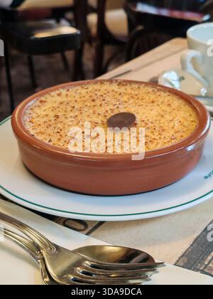 Paris, France - 12 septembre 2025 : gros plan sur un dessert classique à la crème brûlée servi dans un ramequin brun sur de la vaisselle de marque au légendaire Café de Banque D'Images