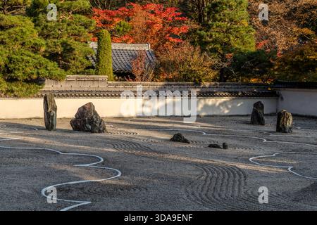 Un jardin de karesansui baigné par le soleil du soir : des zones plates de sable uniformément râtelé et de rochers dispersés projettent de longues ombres ; le cordon blanc divise le jardin en sections courbes, Kiso, préfecture de Nagano, Japon Banque D'Images