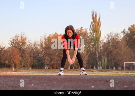Femme athlète mature faisant des exercices d'étirement d'échauffement au stade Banque D'Images