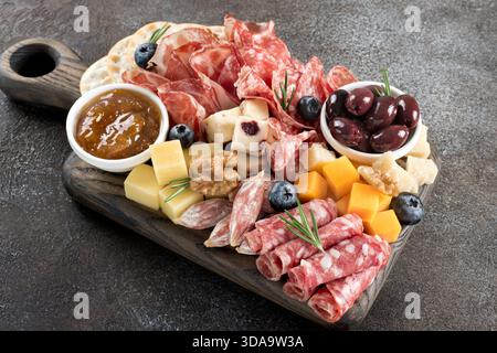 Gros plan de la charcuterie avec assortiment de fromages, viandes, olives, confiture, craquelins et baies. Banque D'Images