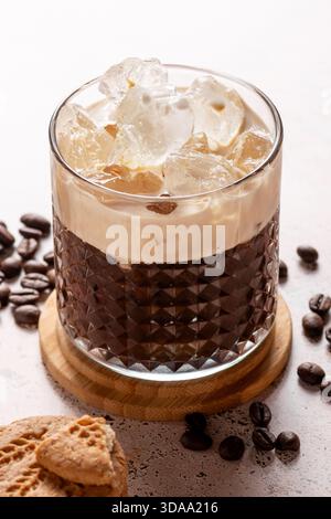 Café glacé crémeux espresso avec grains de café éparpillés sur la table en pierre texturée, gros plan Banque D'Images