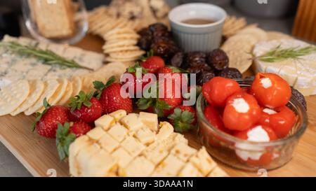 Belle planche de charcuterie avec fromages assortis, fruits frais, dattes et poivrons farcis au fromage à la crème. Parfait pour le partage, les fêtes ou l'application élégante Banque D'Images