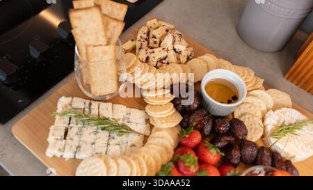 Belle planche de charcuterie avec fromages assortis, fruits frais, dattes et poivrons farcis au fromage à la crème. Parfait pour le partage, les fêtes ou l'application élégante Banque D'Images